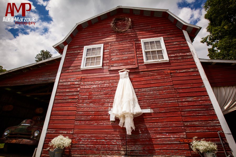 Stunning bridal gown against a large red barn in Seagrove, NC. © Aura Marzouk Photography