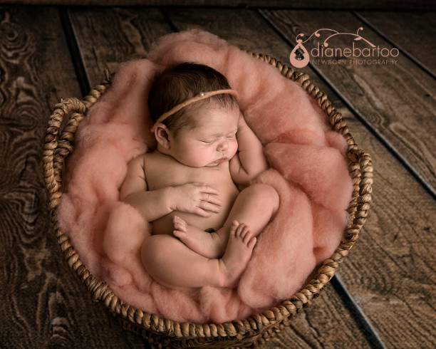 sleeping newborn girl in basket on wood floor