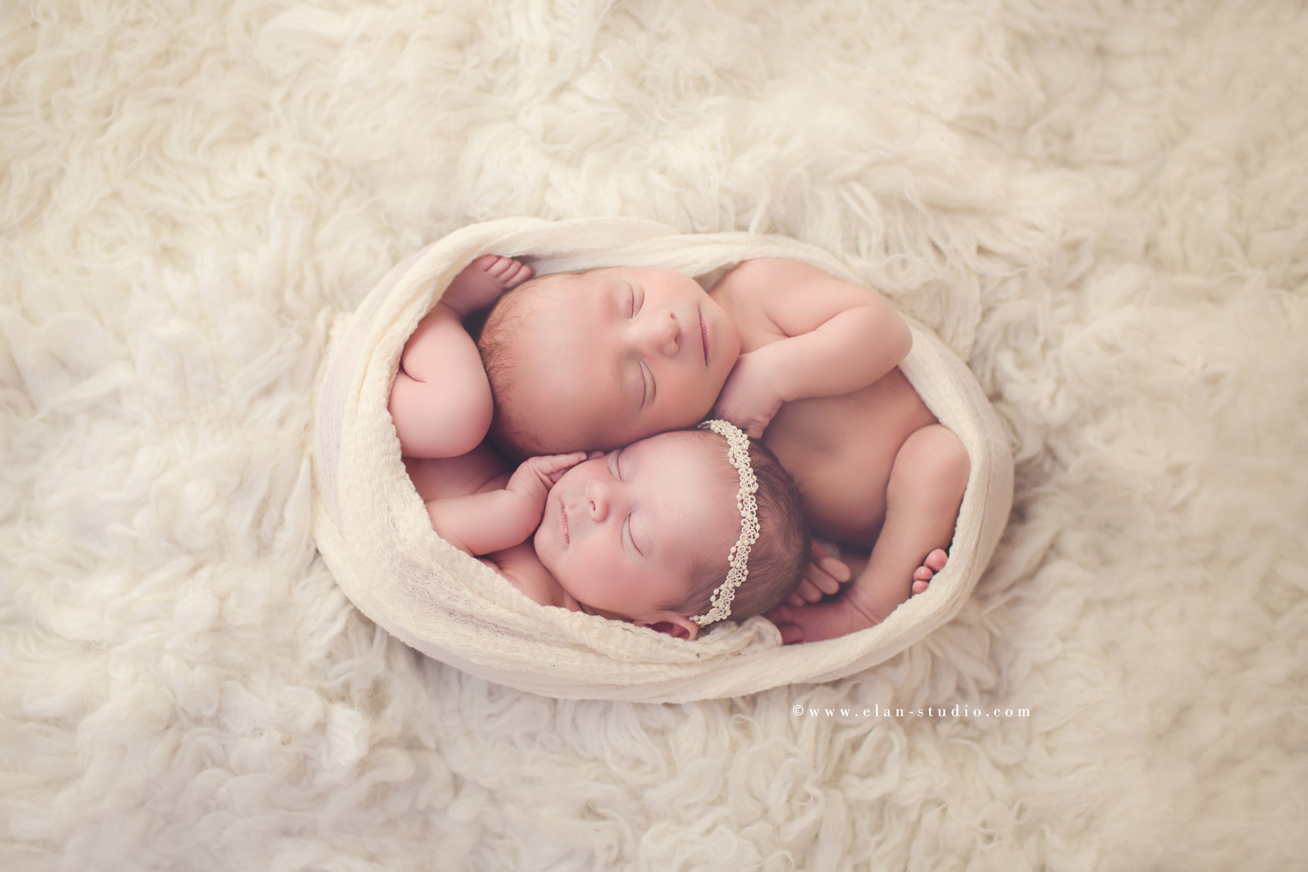 newborn twins in gauze wrap on fur rug