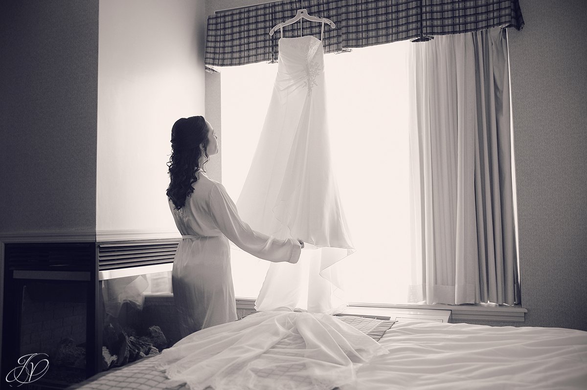 black and white photo of bride looking at her dress