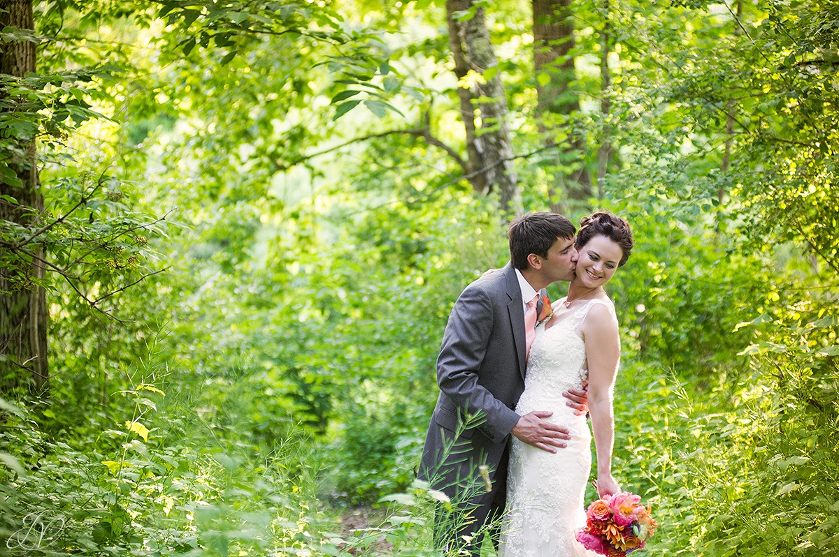 romantic shot of groom kissing bride in woods