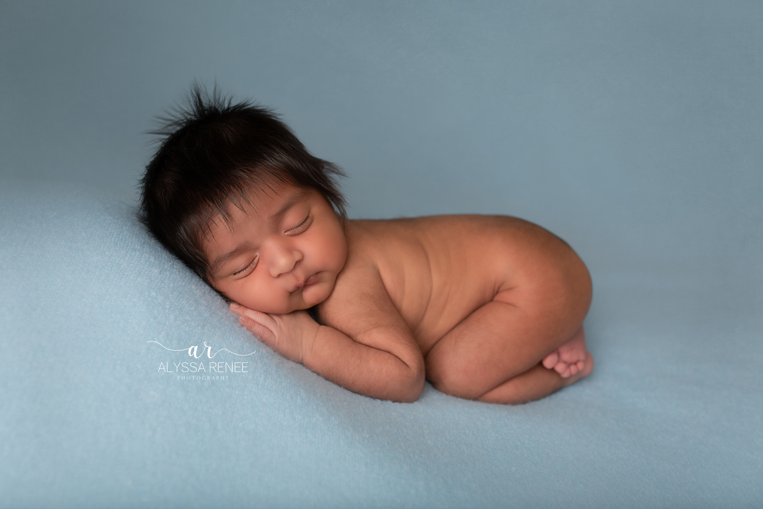 Baby in artistic portrait with blue blanket with a blue background