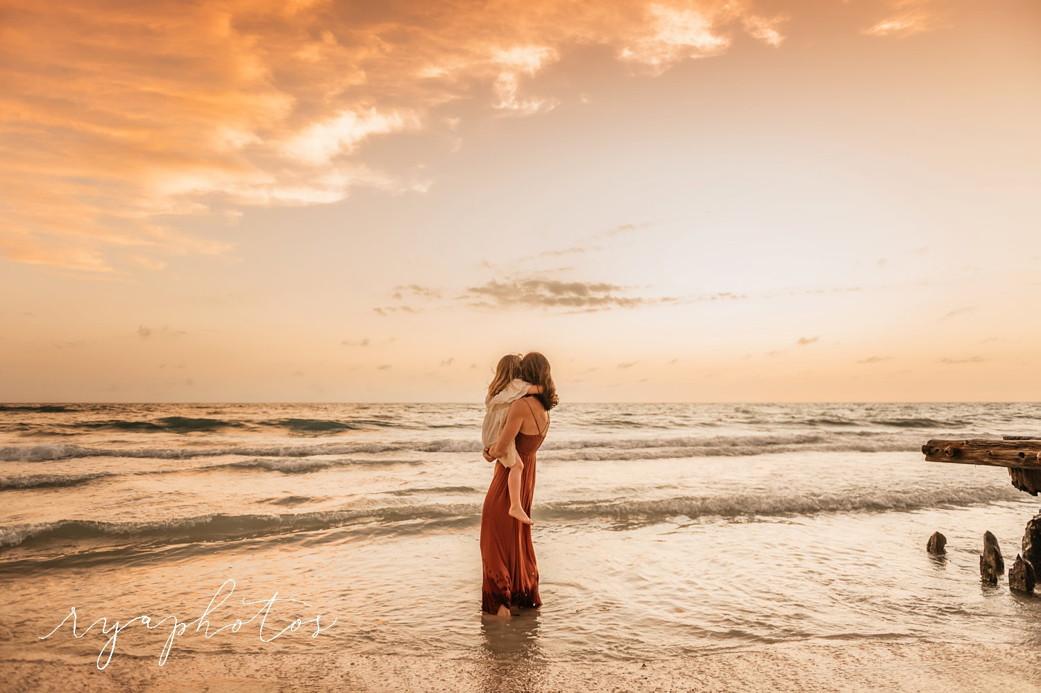 mother holding young daughter at the beach at sunset, Florida, Ryaphotos