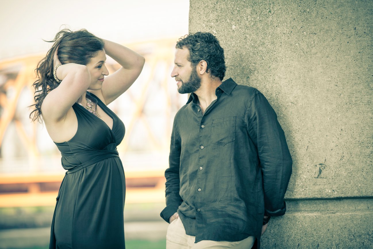 A man and woman stand near a concrete column outdoors, engaging in conversation. Burlington Skyway bridge