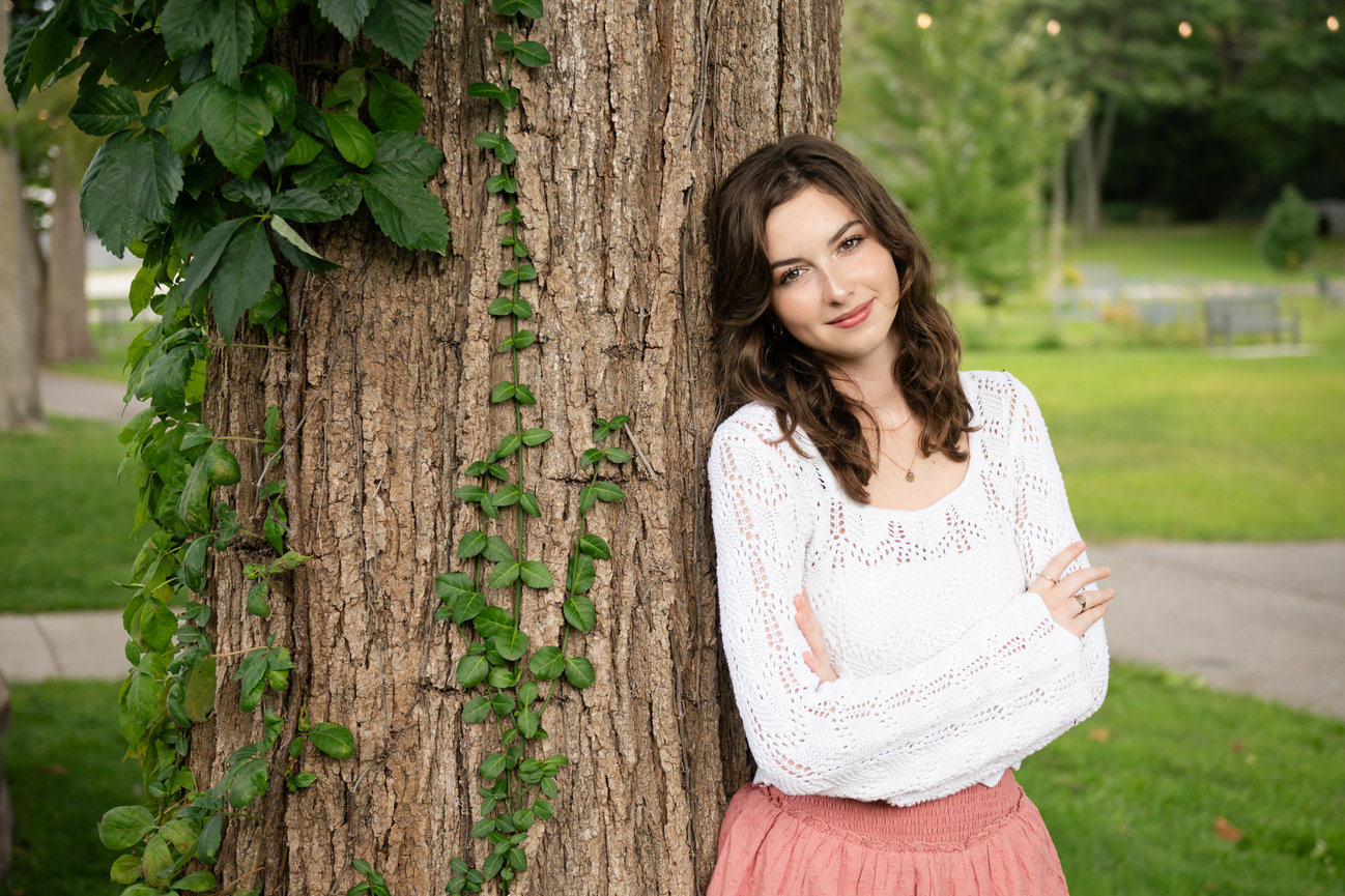 high school senior girl leaning against tree in downtown clarkston depot park