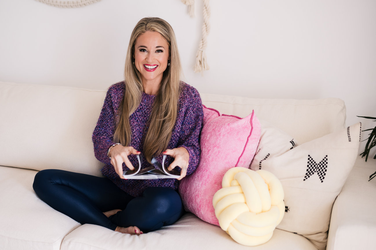 female entrepreneur life coach shuffles tarot cards while cross legged on couch for personal brand photo