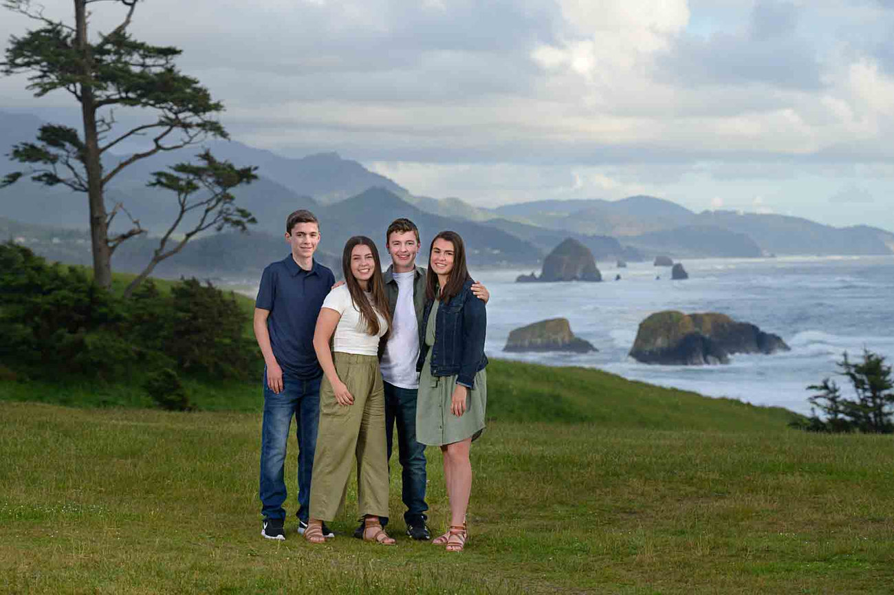 Siblings posing together at Ecola State Park with a view of Haystack Rock
