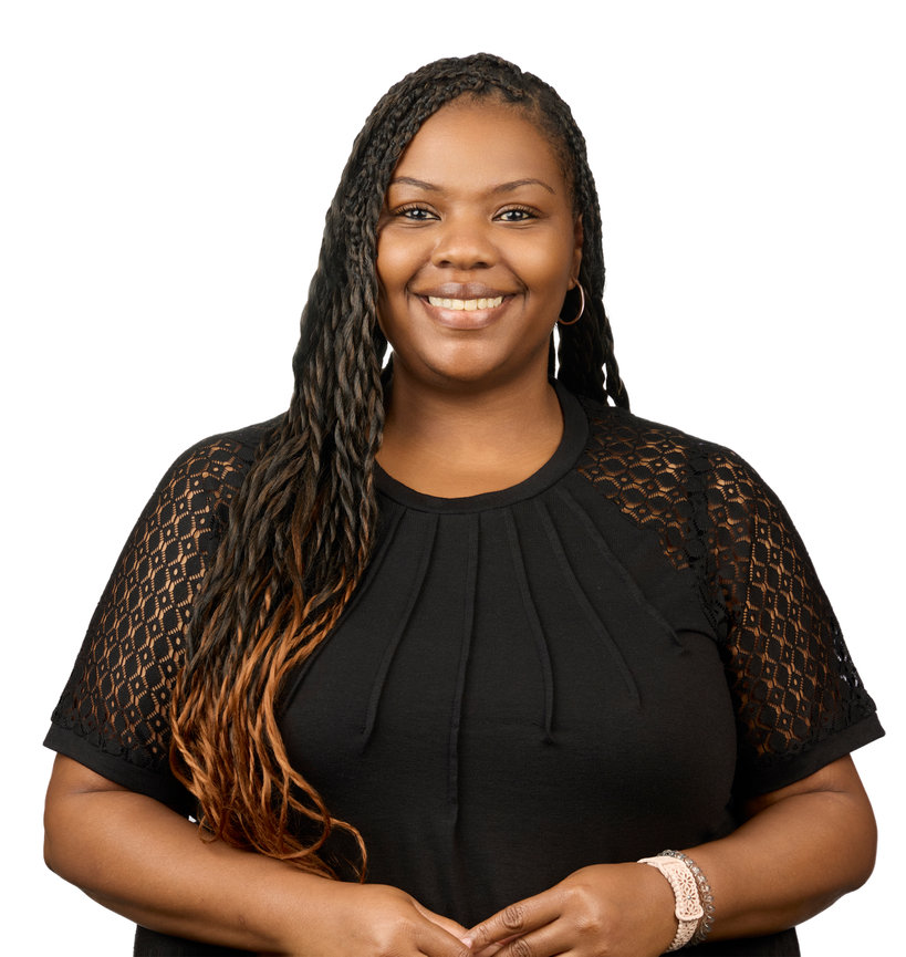 Smiling person with long braids wearing a black top against a white background.