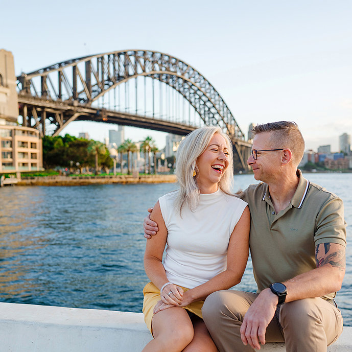 Portrait of couple lovingly looking at each other and laughing in Sydney with Sydney harbour in background