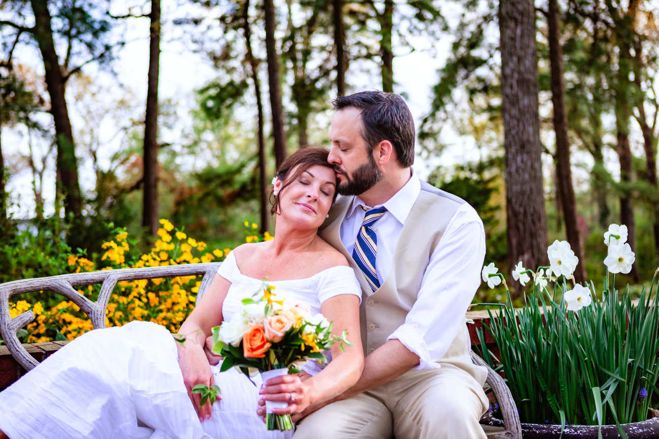 Groom kissing his bride’s forehead as she smiles softly, surrounded by yellow blooms during their romantic micro wedding captured by gulf coast photographer Dixon Creative Images