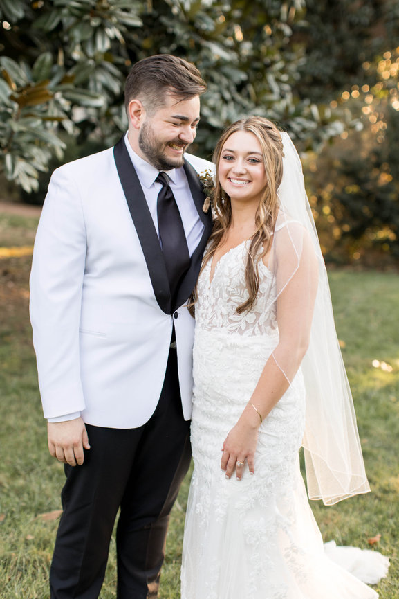 Bride smiling at the camera while her groom is smiling at her