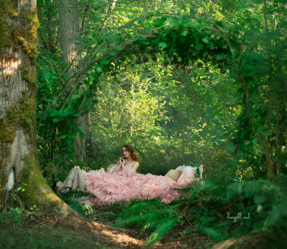 Woman reclining in a pink dress among greenery and arches