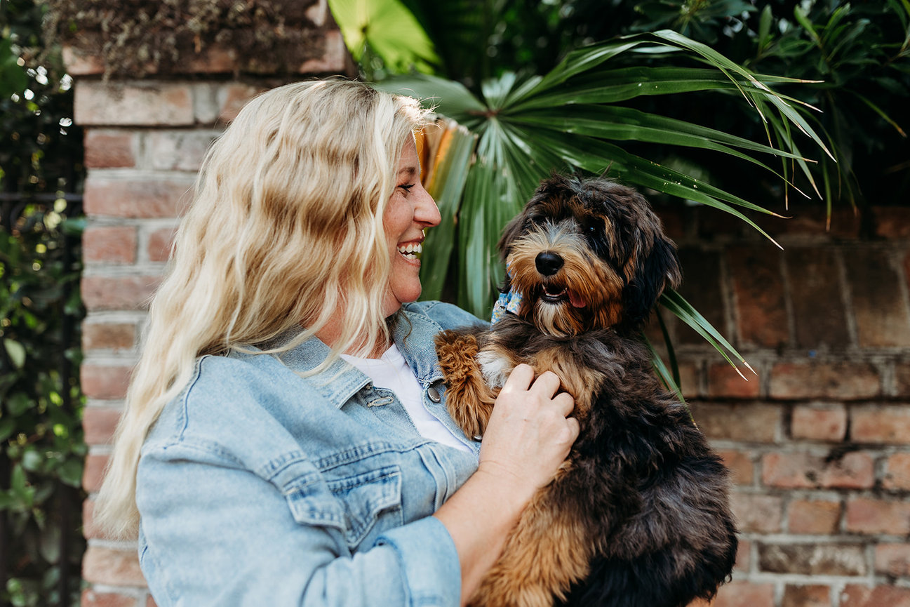 A blond woman holds a small black and brown dog