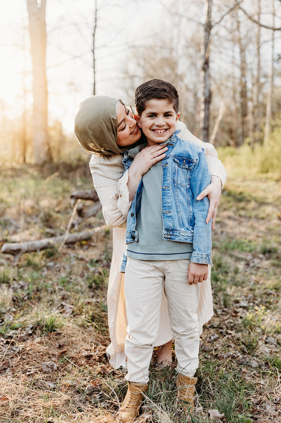 a mother in a hijab puts her hands on her sons shoulders and smiles at him during a Huntsville, Alabama photoshoot