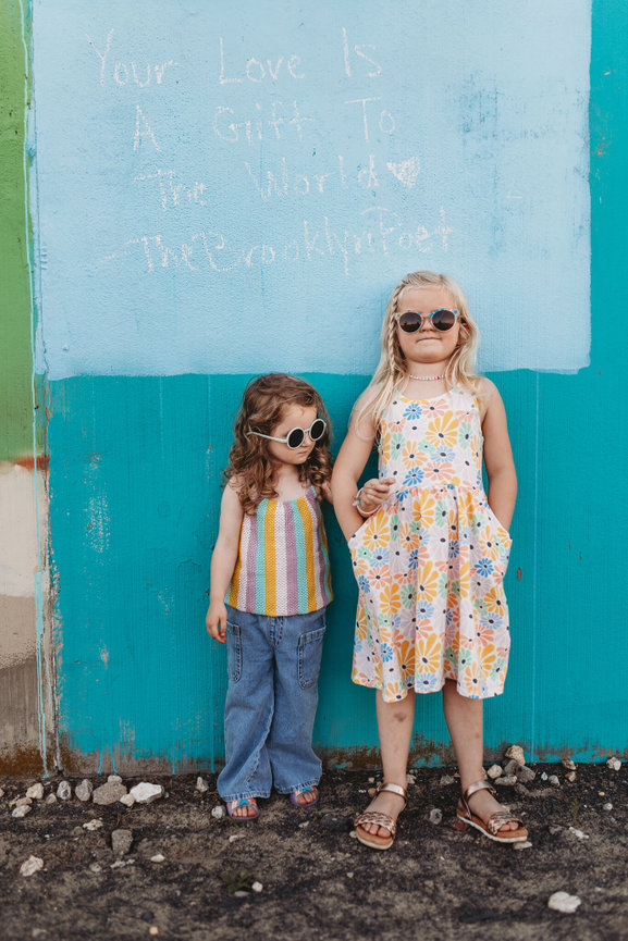 Two sisters wearing sunglasses standing next to each other on the Asbury Park Boardwalk.