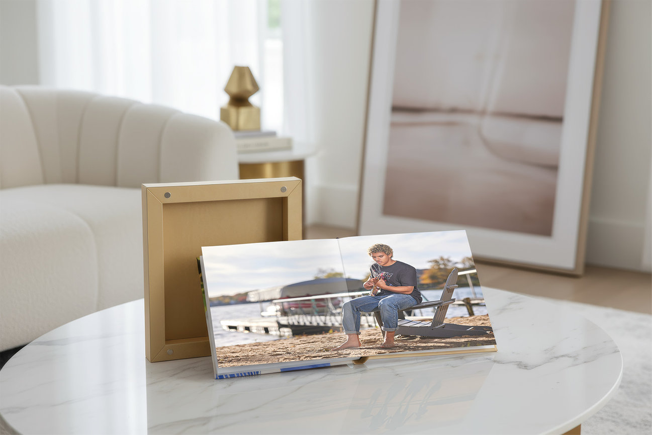 High school senior portraits of a male student displayed in a handcrafted album on a table, showing a refined and tangible way to enjoy portrait artwork at home