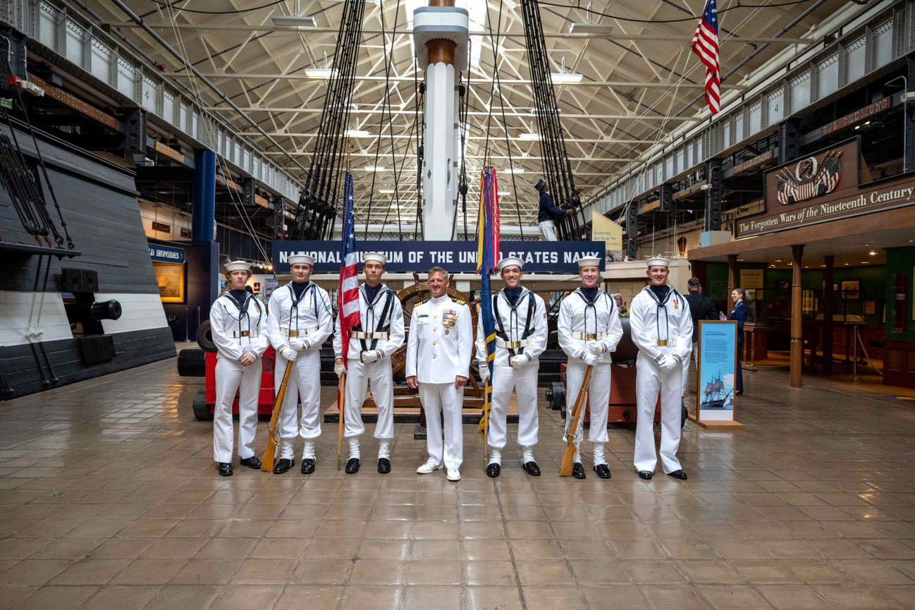 Naval Officer posing in choker white uniform with the ceremonial color guard
