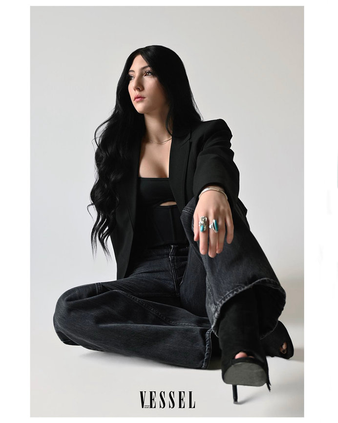 A professional branding portrait of a woman sitting confidently in black attire, featured in Vessel Magazine, based in Salt Lake City, Utah. Empowering businesswomen and entrepreneurs. Photo shoot by Tre Nelson Photo.