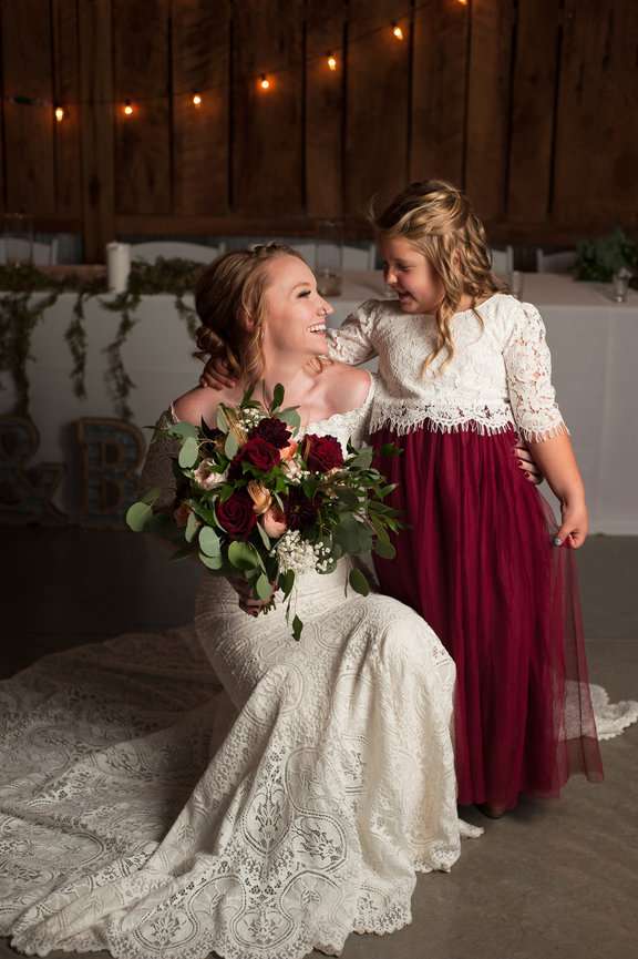 Bride smiling with flower girl before her wedding.
