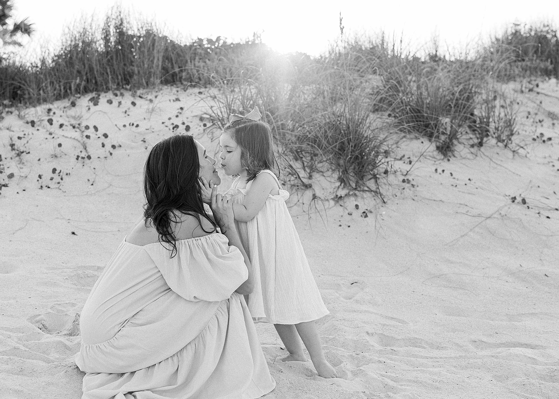 woman and little girl kissing on the sand