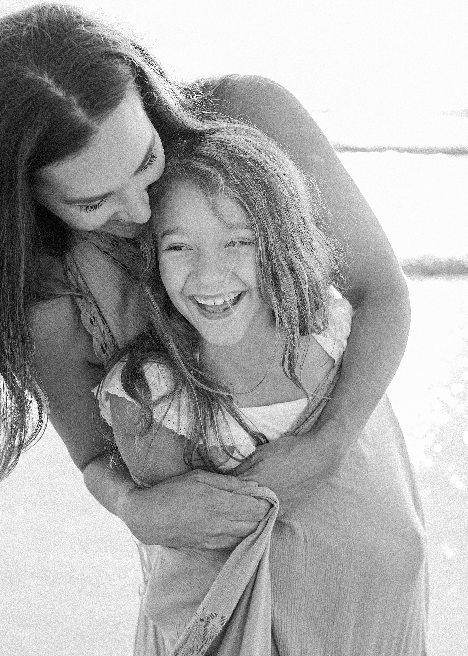 woman smiling with daughter in black and white on the beach