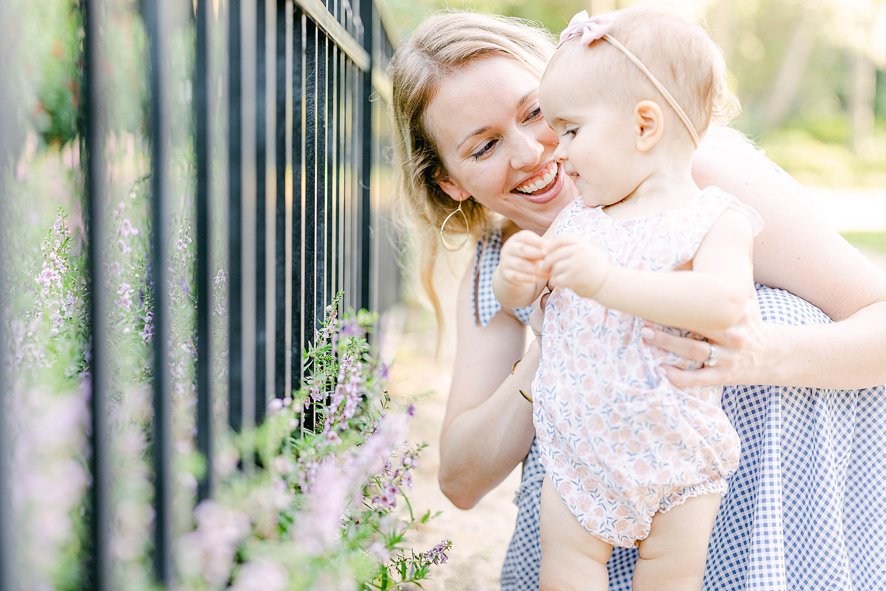 woman holding baby girl by purple flowers smiling