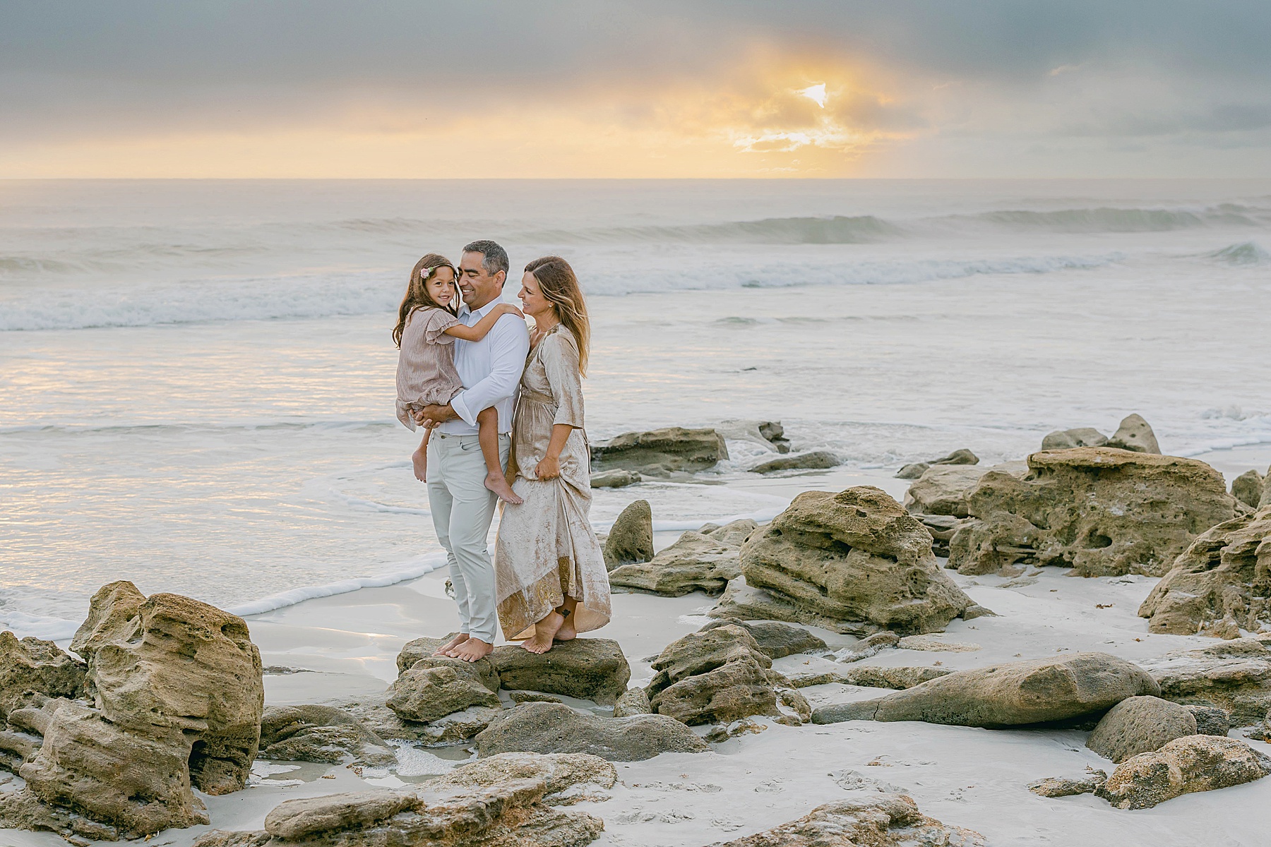 family standing on the beach together at sunrise in florida