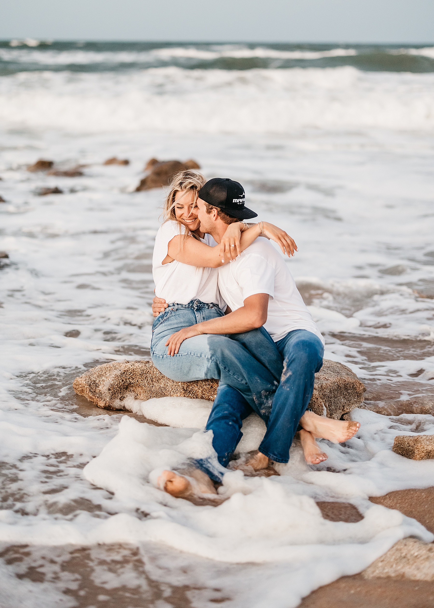 woman standing in the waves at the beach with man in jeans
