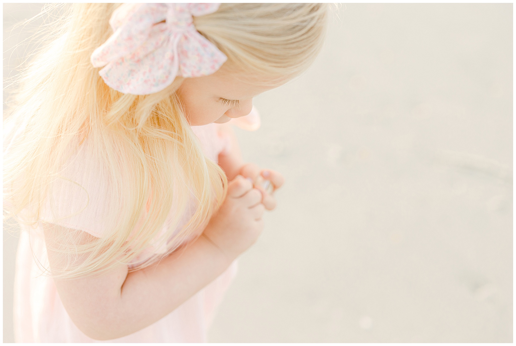 little blond haired girl with pink bow in her hair and pink dress on the beach in saint augustine florida