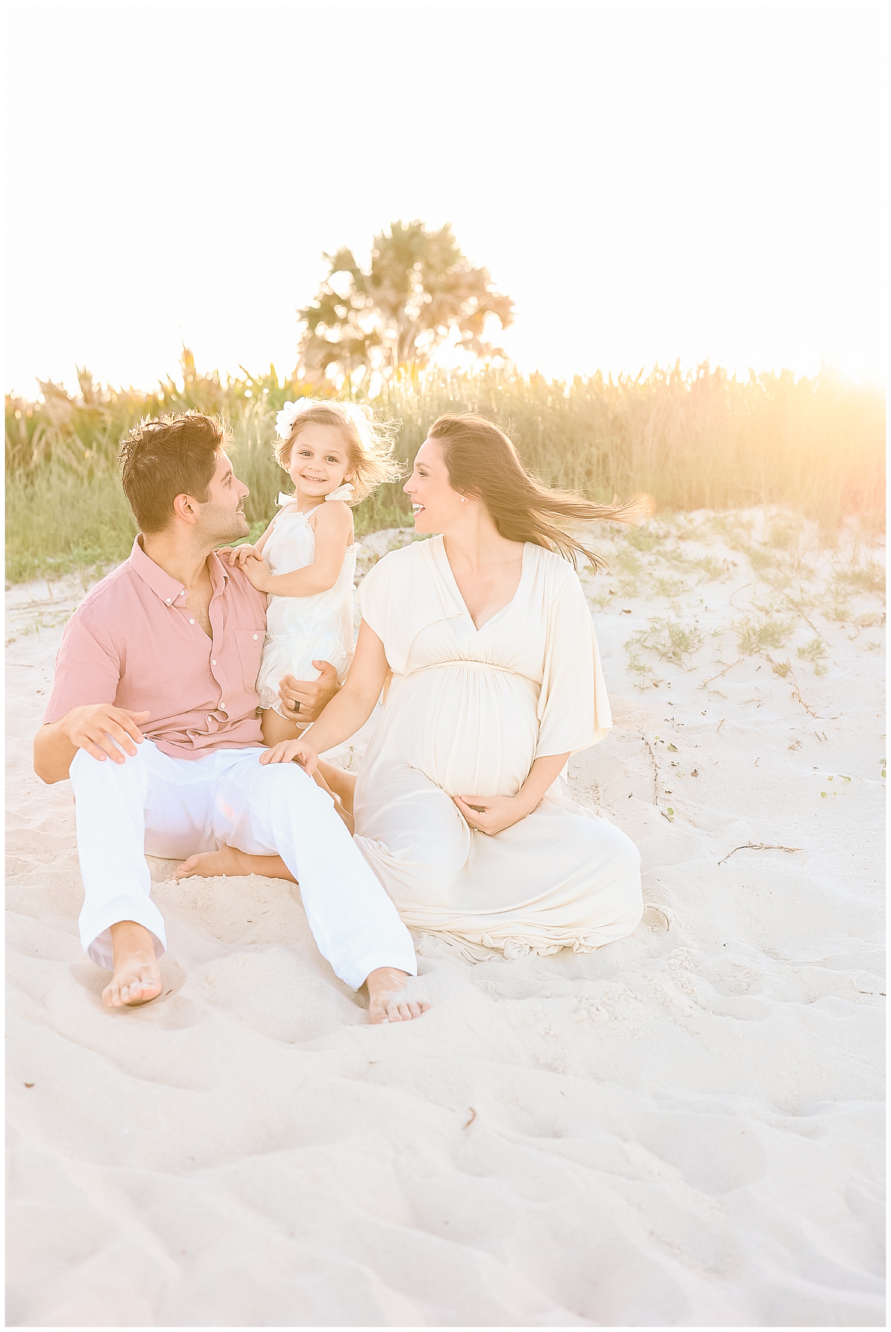 family sitting on the sand on the beach in saint augustine florida at sunset