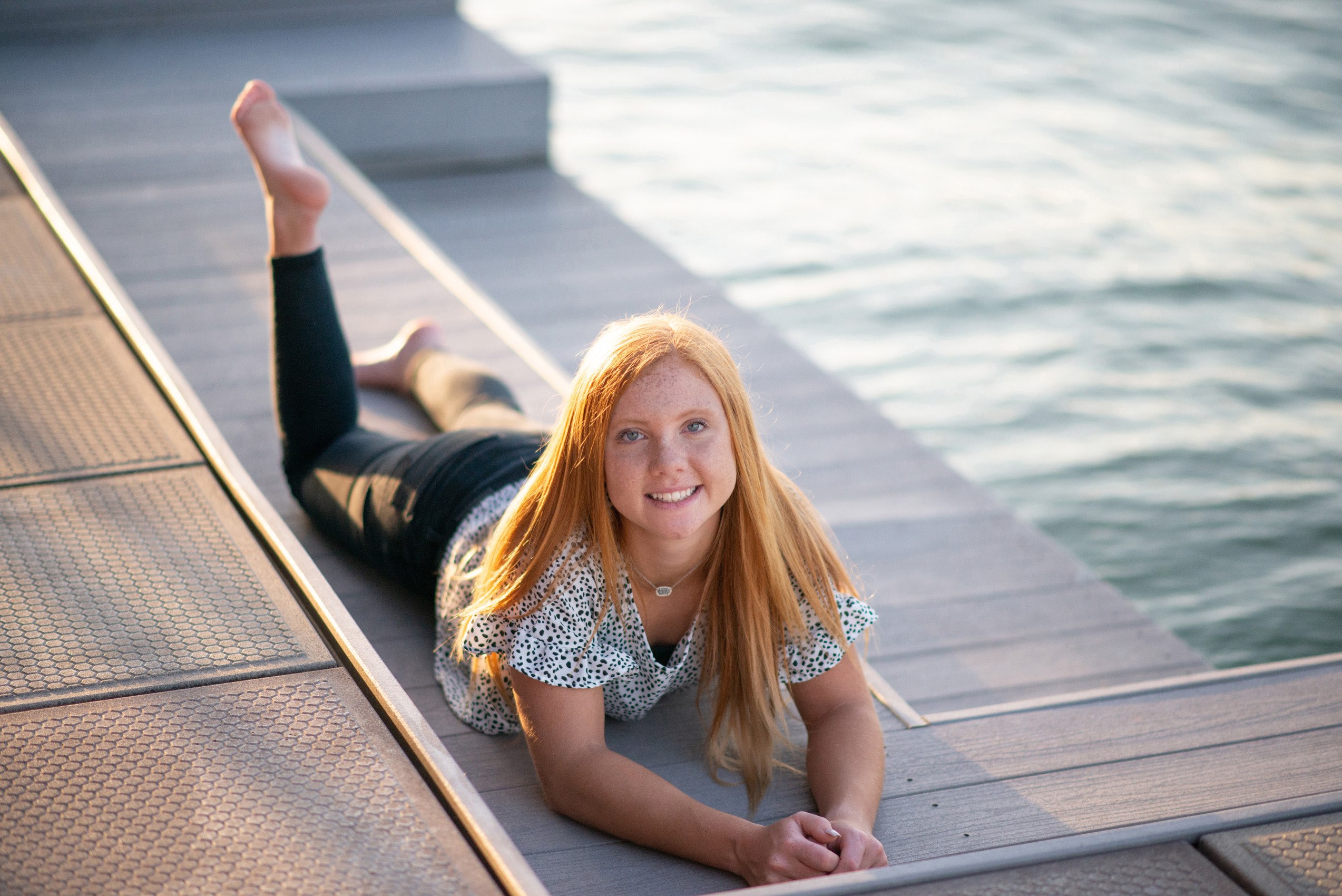 Senior girl with red hair laying on the dock at a Tablerock Lake dock. 