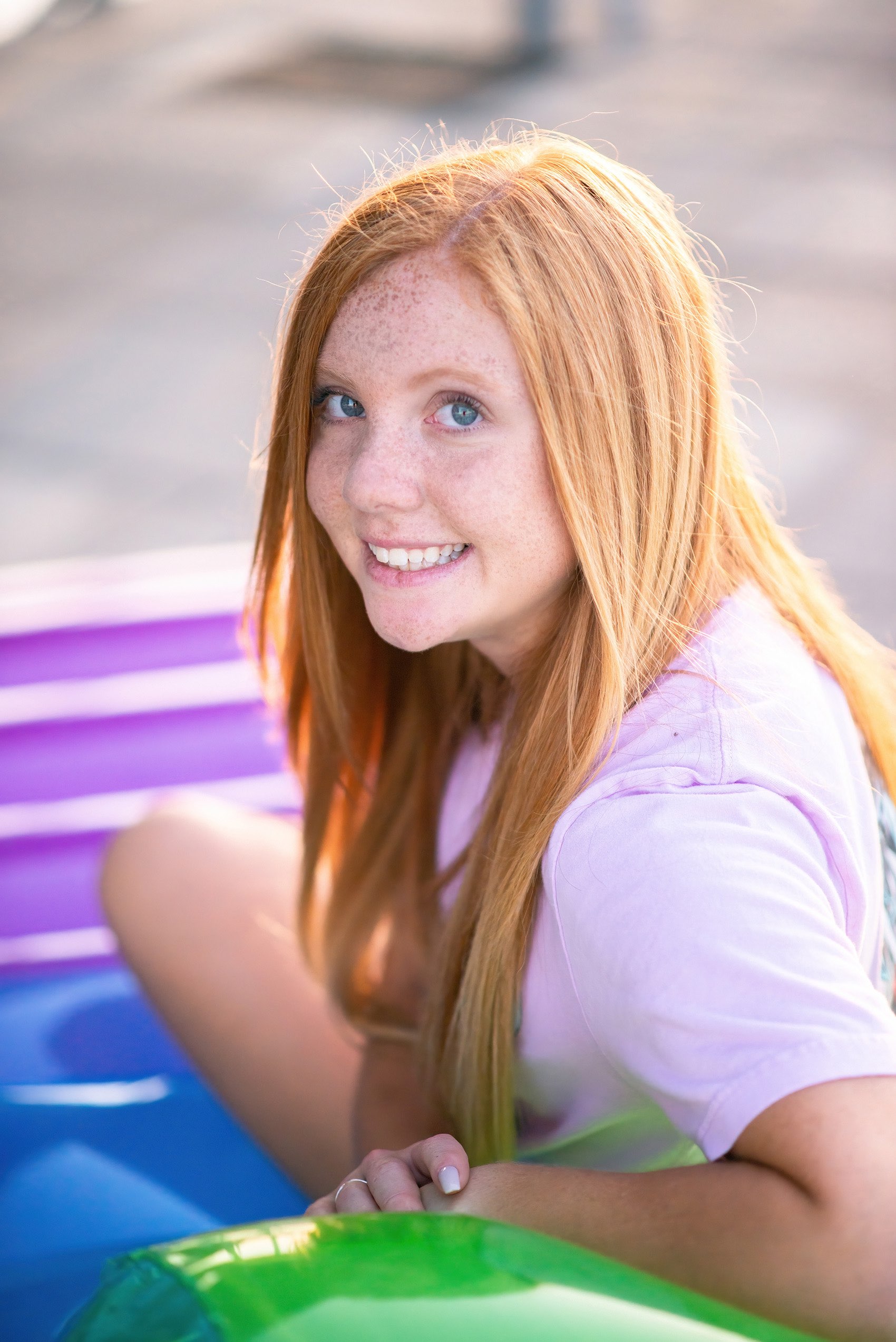 Senior girl in pink tshirt sitting on colorful loung chair on dock at Tablerock Lake.