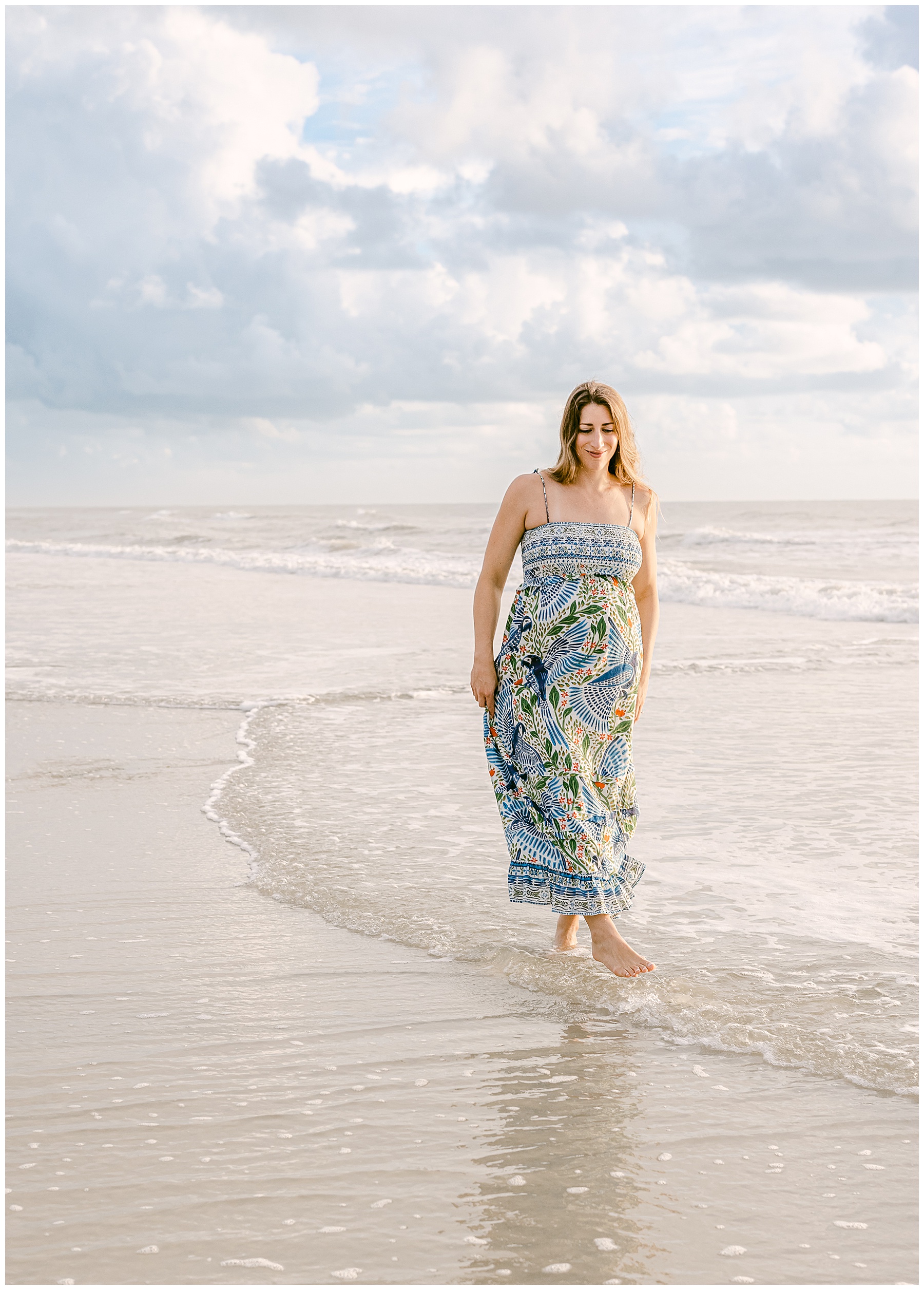 maternity portrait of woman in fair rio maxi dress walking on the beach at sunrise