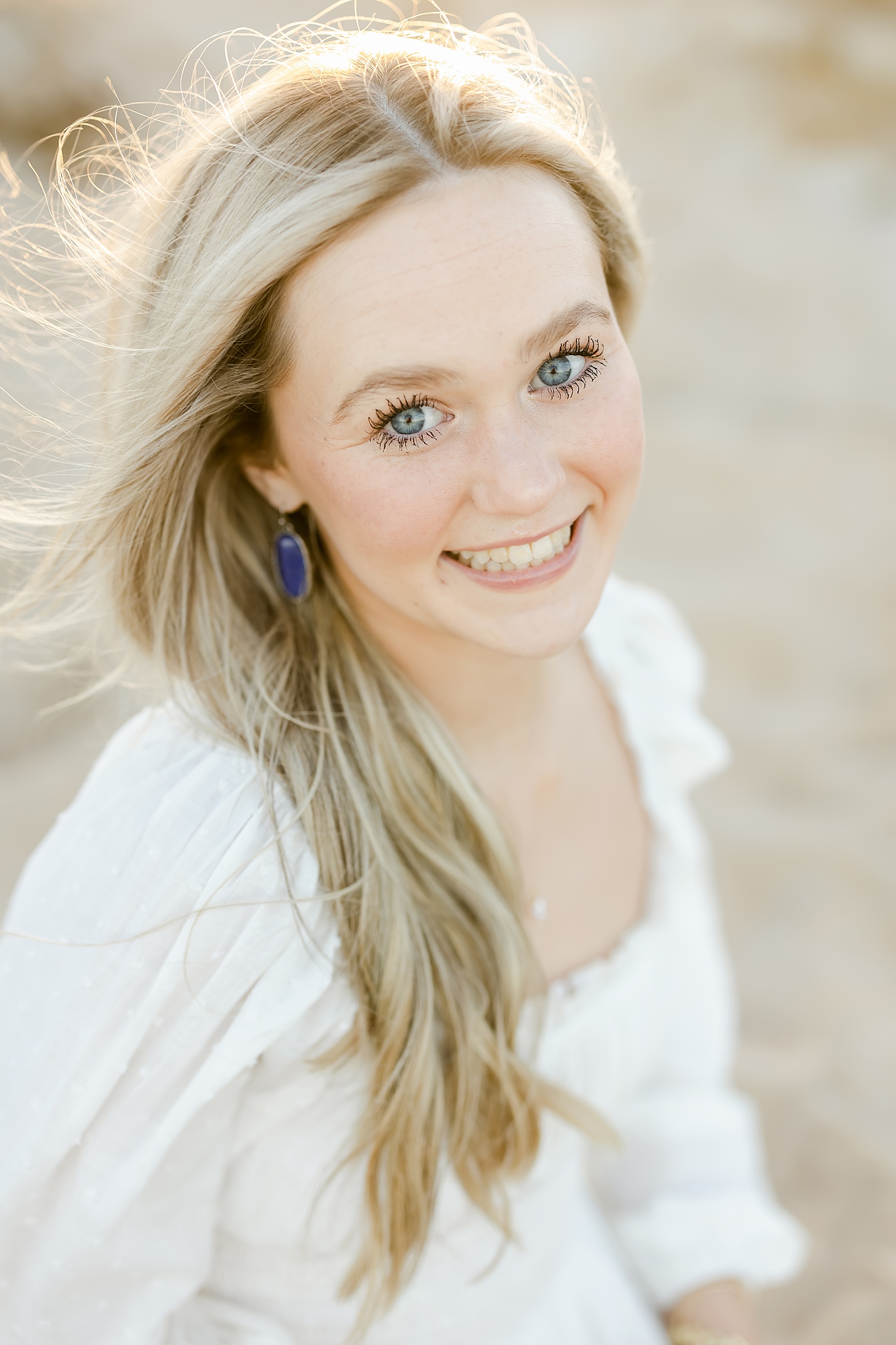 blue eyed blonde hair young woman wearing white dress smiling at the camera