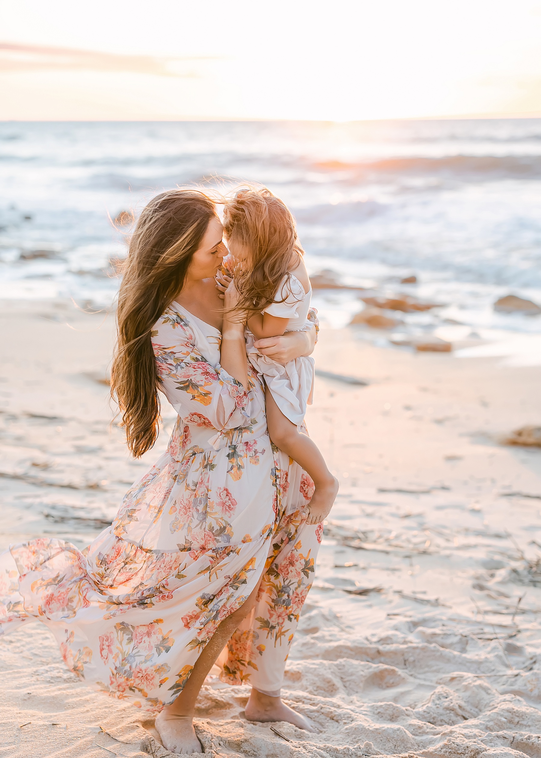 woman with long brown hair holding baby girl on the beach at sunrise in st. augustine florida