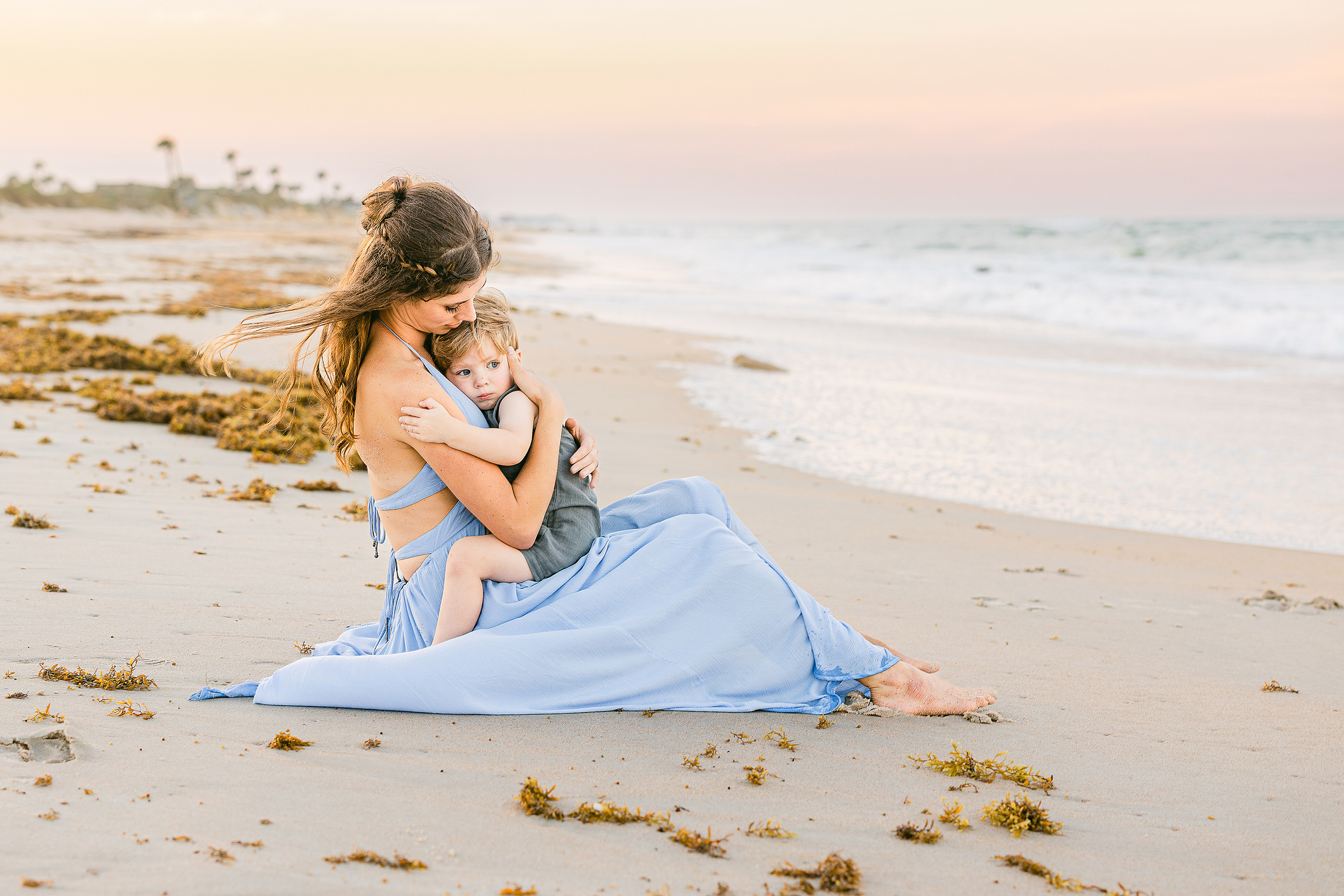 pastel-hued image of woman with little boy on the beach at sunset