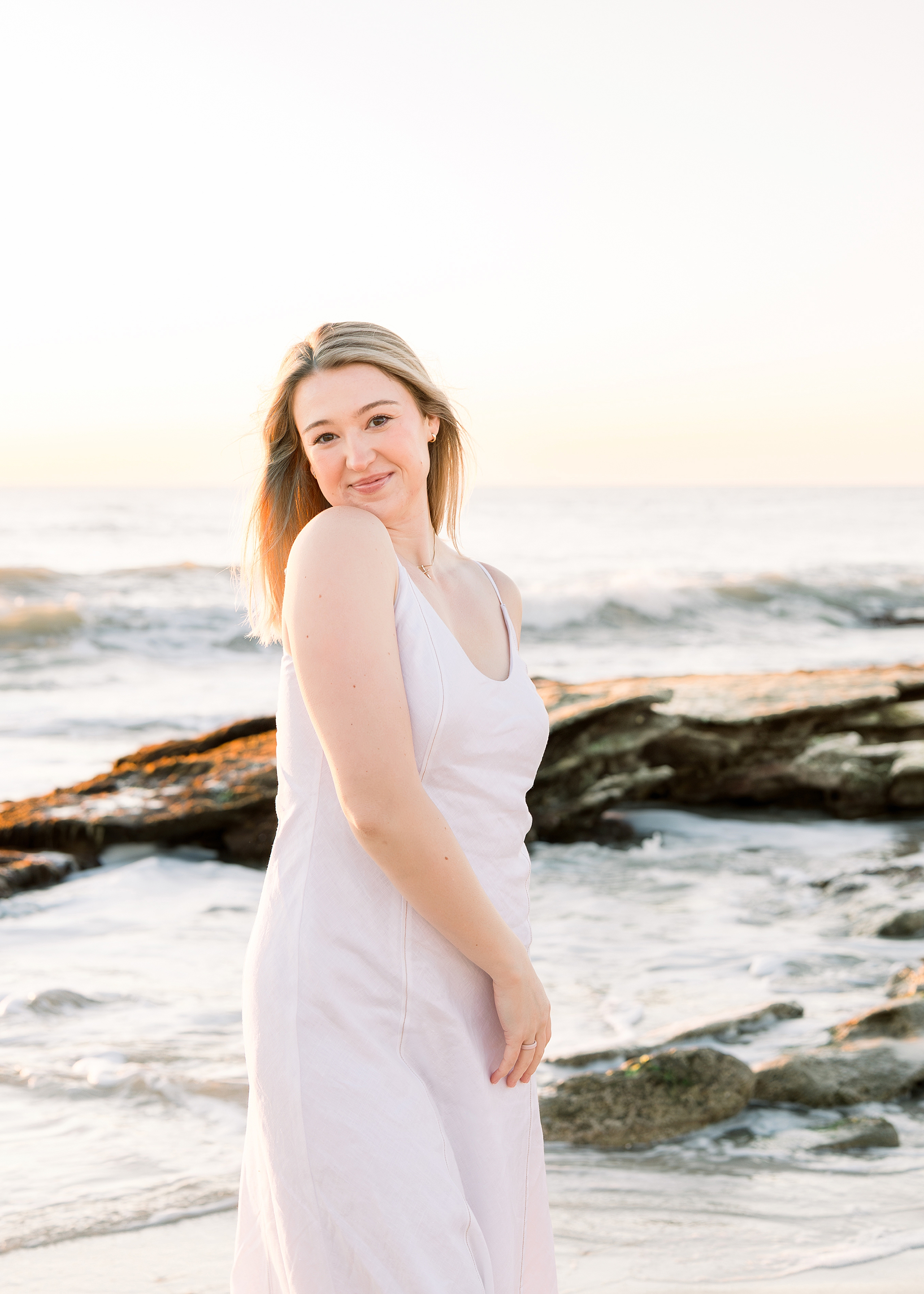 A sunrise portrait of a young woman dressed in white on the beach in Saint Augustine, Florida.