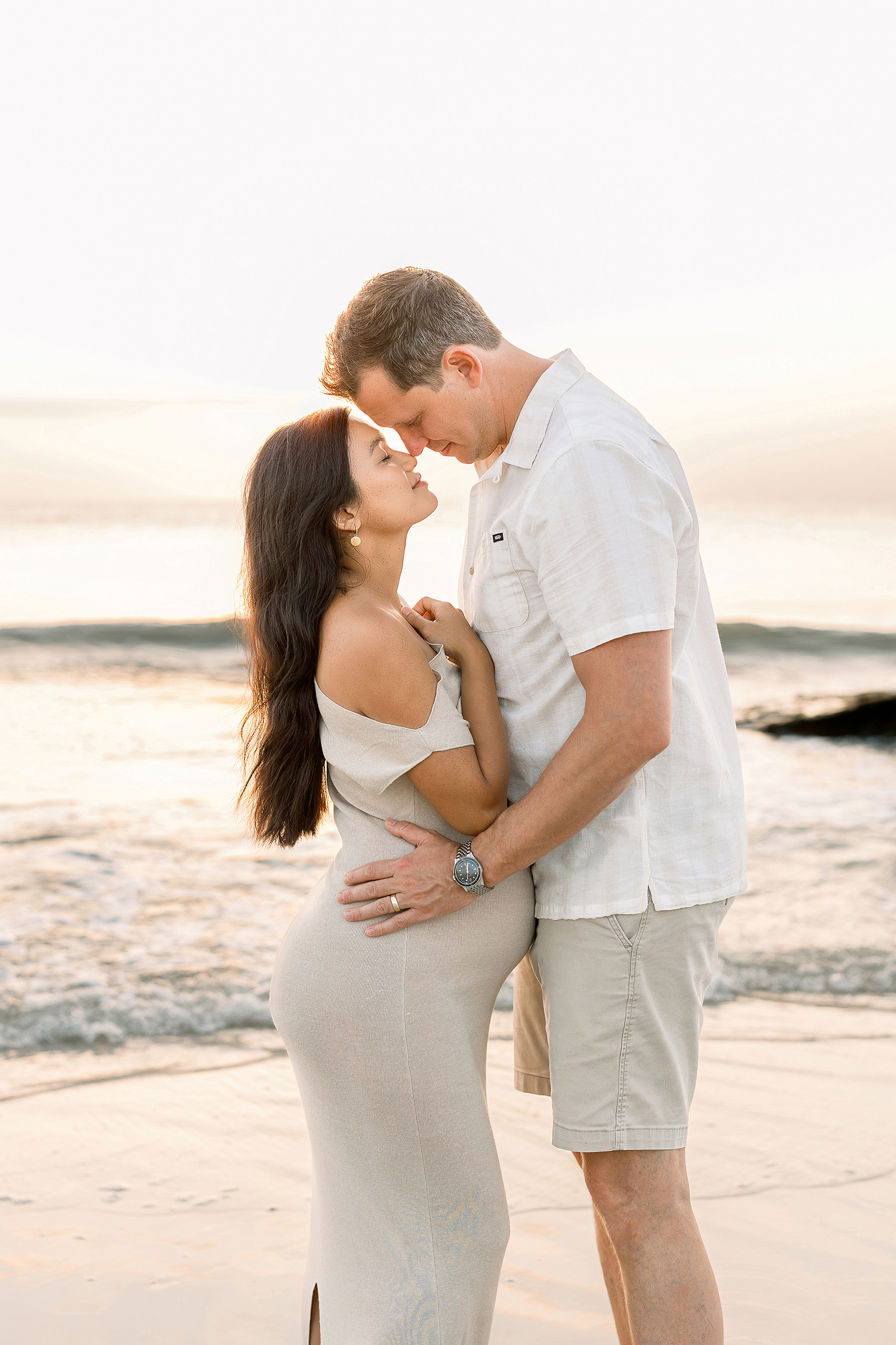 A sunrise beach maternity portrait of a couple on the beach at sunrise.