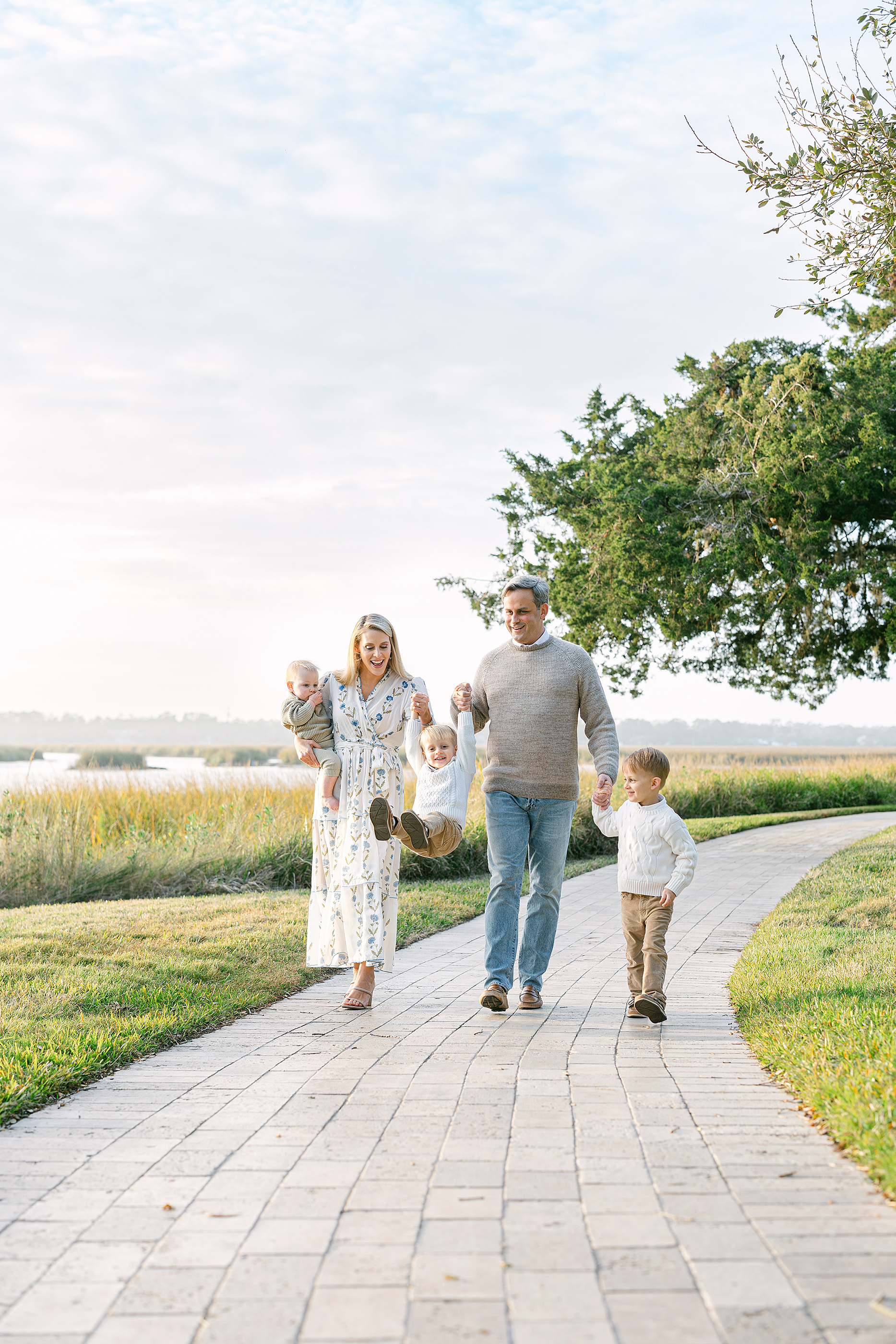 A family swings their little boy in the air as they walk along a path near the intracoastal.