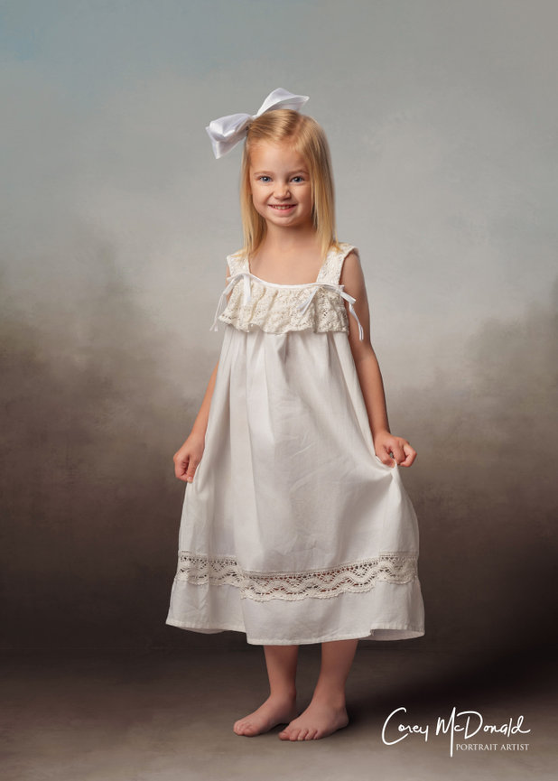 Young girl in white dress with lace, large white bow in hair, barefoot, smiling, standing against a softly blurred background.
