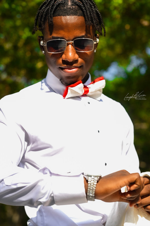A young man sporting a bow tie and sunglasses, exuding a stylish and confident demeanor.