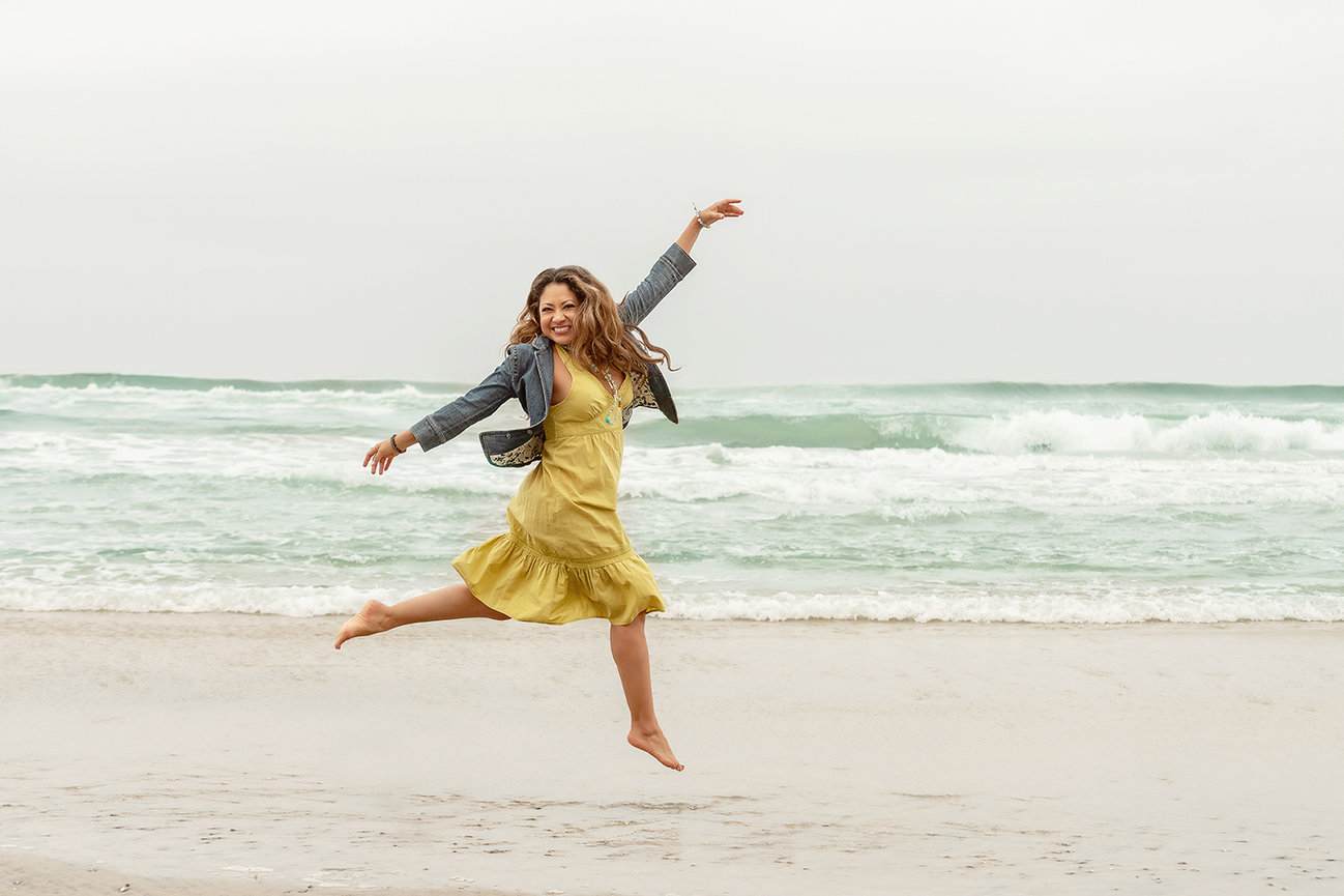 Woman in yellow dress at beach, running and jumping in air, by Southern California Branding and Lifestyle Photographer, Stefanie Blue.