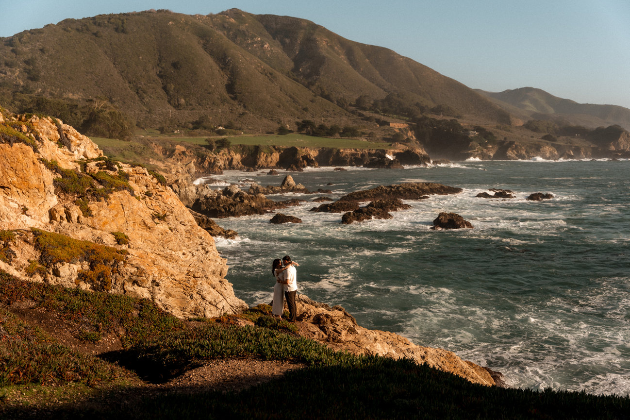 Couple standing on a hill overlooking the ocean