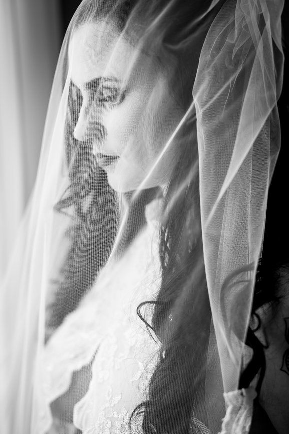 Black and white portrait of a woman's profile, partially obscured by a sheer, layered veil.