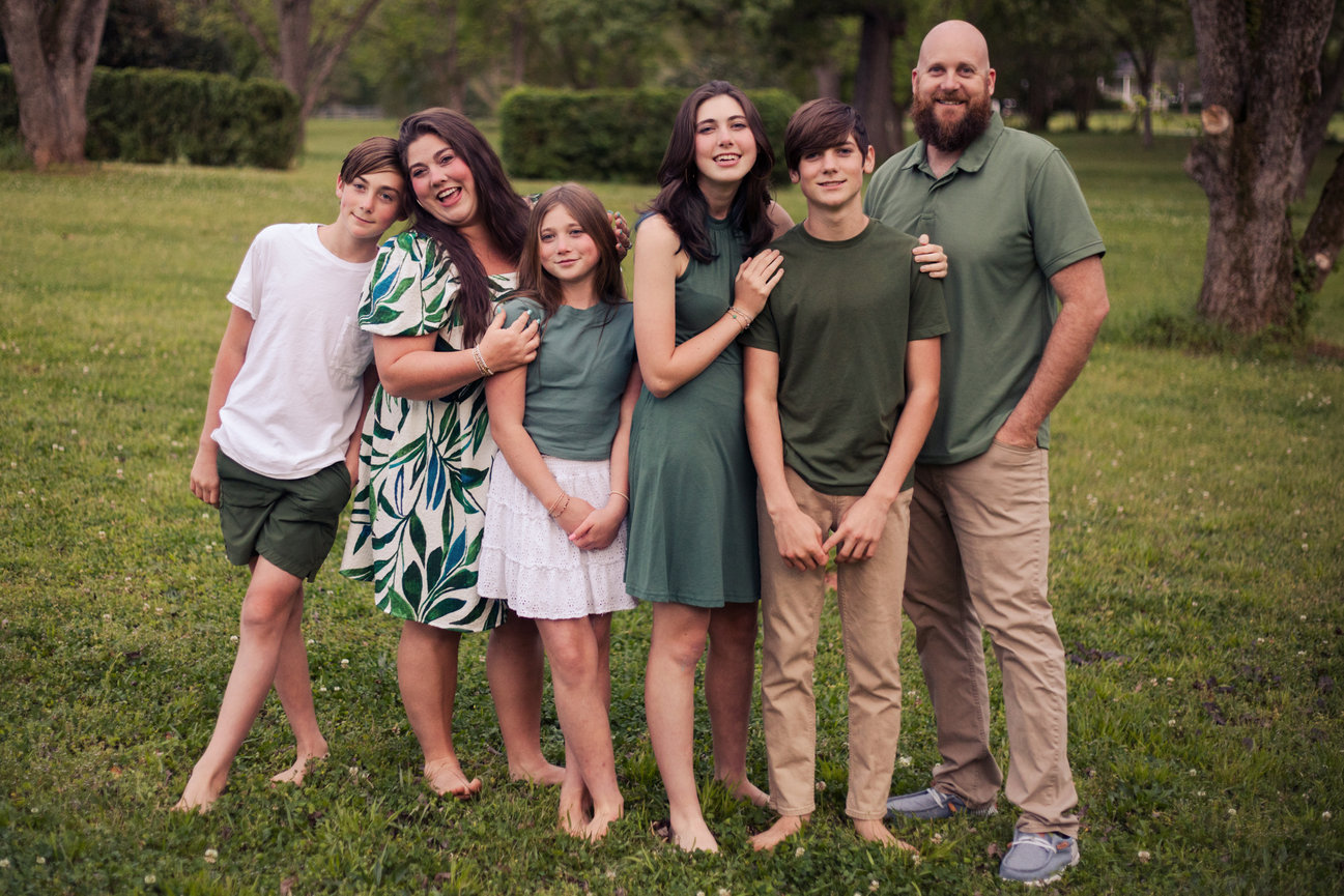 Large family group posing together on a grassy lawn in a park.