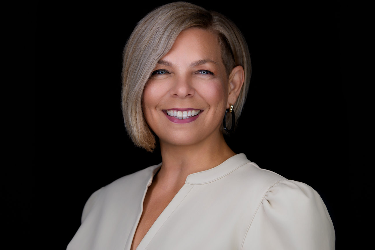 Corporate headshot of confident woman with short blonde hair in cream blouse, photographed in a professional portrait studio