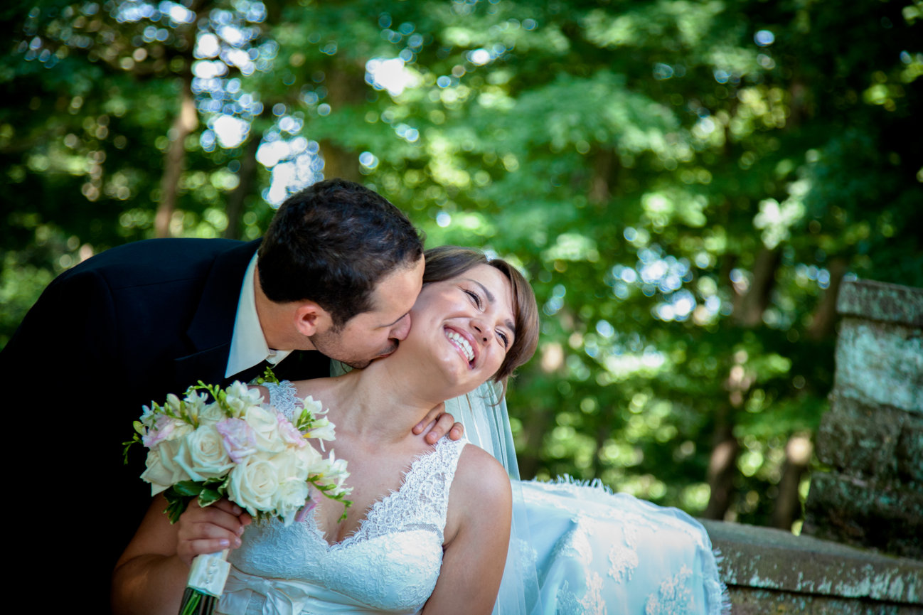 Groom kissing bride's neck, both smiling