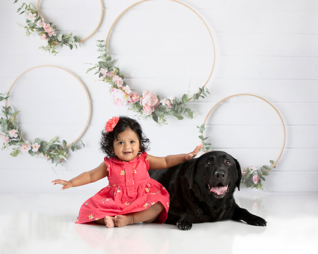 Girl in pink dress sitting with a black dog