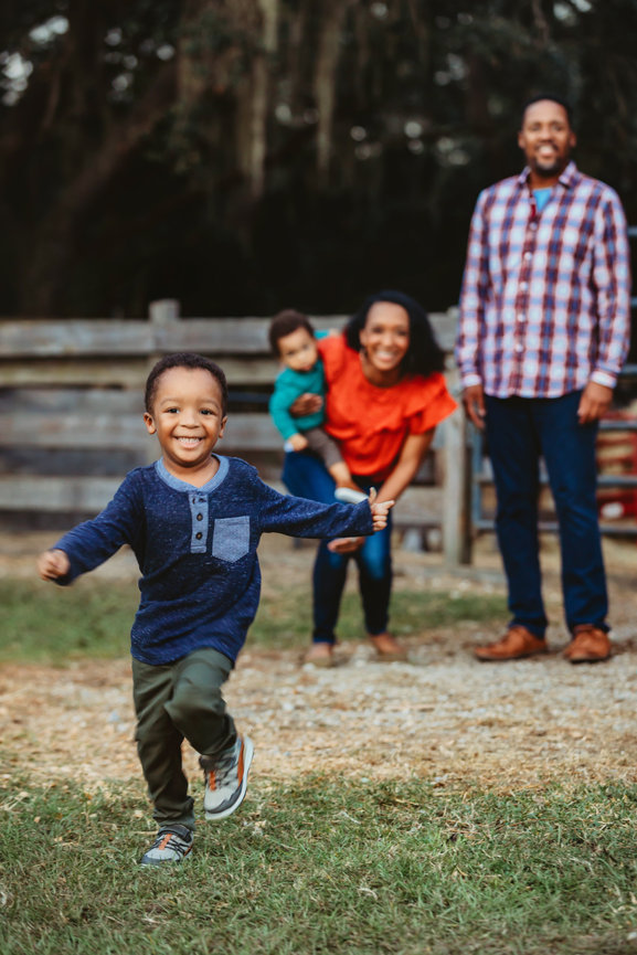 Child running from family smiling during family photos at Cheyne Ranch in Oviedo Florida.