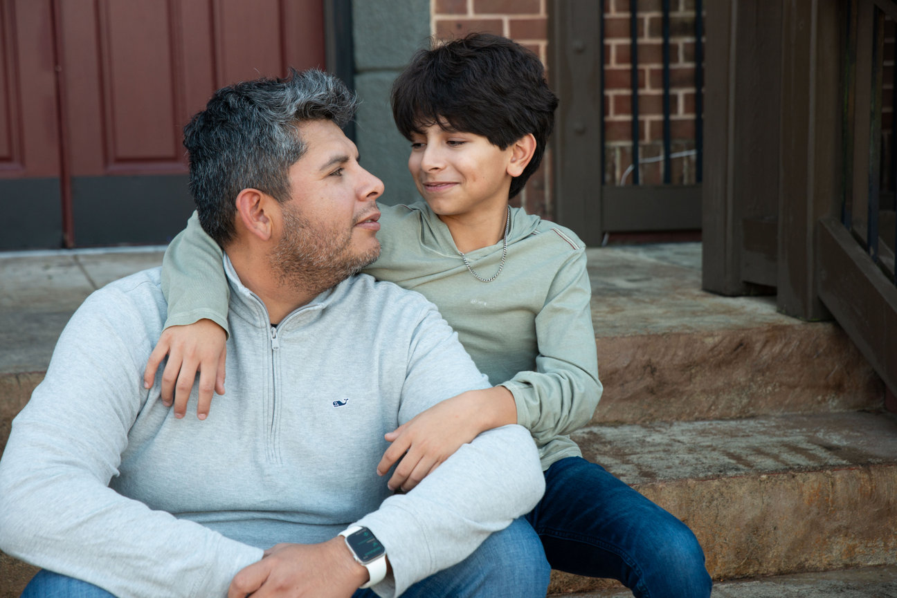 Parent and child sitting together on outdoor steps and smiling.